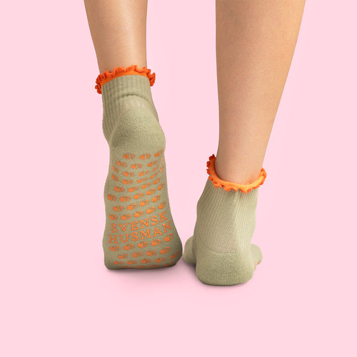 Beige pilatesstrumpor med halkskydd, orangea detaljer och texten Svenskhusman på undersidan.