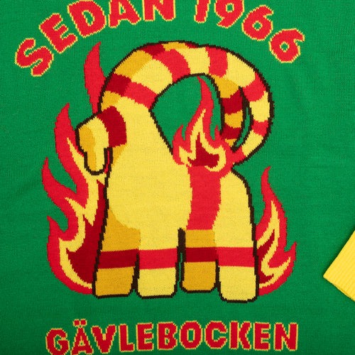 Grön stickad jultröja med motiv av den brinnande Gävlebocken och röd text från Svenskhusman.