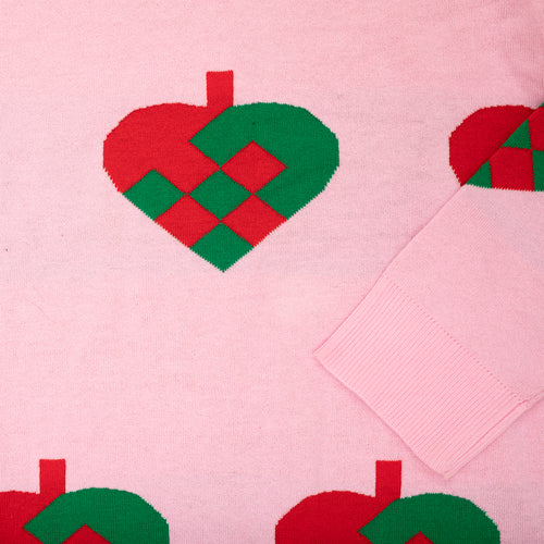 Rosa stickad jultröja med mönster av röd-gröna flätade julhjärtan från Svenskhusman.