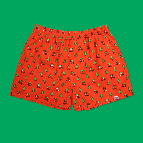 Röda boxershorts med mönster av bilar med julgranar från Svenskhusman mot en grön bakgrund.