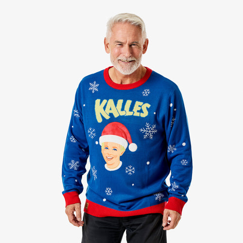 Blå jultröja med Kalles Kaviar-motiv, snöflingor och röd mudd på en leende modell från Svenskhusman.