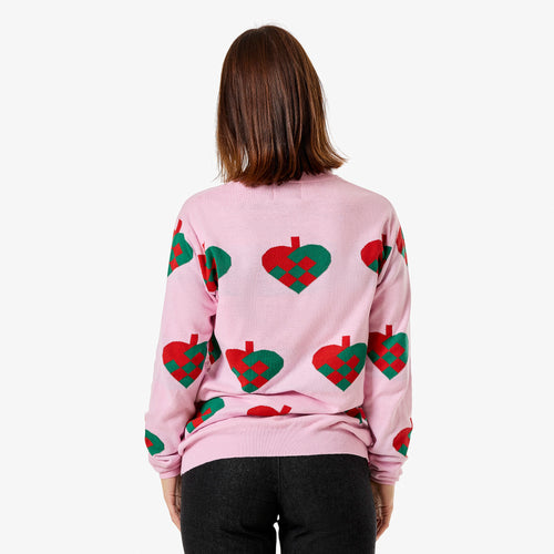 Rosa stickad jultröja med mönster av flätade julhjärtan på en kvinna sedd bakifrån från Svenskhusman.