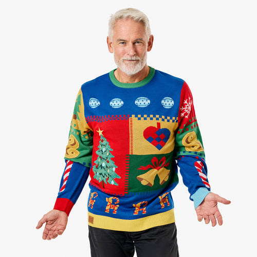 Man i en färgpatchad jultröja med julgrans- och hjärtmönster från Svenskhusman på vit bakgrund.