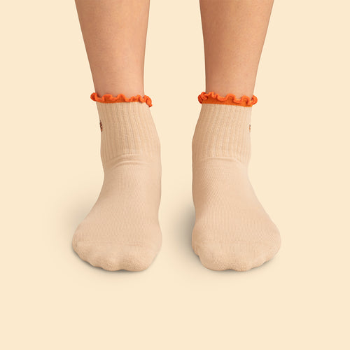 Beige pilatesstrumpor med kanelbulle-motiv och orange volangkant på fötterna från Svenskhusman.