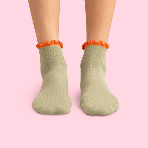 Beige pilatesstrumpor med dammsugarmotiv och orange vågig kant på fötter mot rosa bakgrund från Svenskhusman.