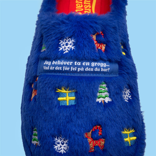 Blå fluffiga tofflor med broderade juldetaljer och texten 