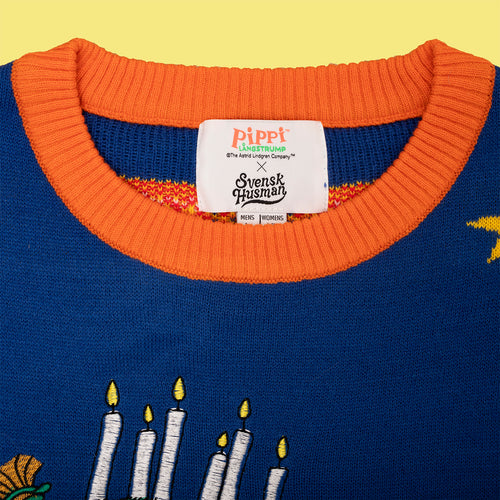 Blå stickad jultröja med Pippi Långstrump lucia-motiv, orange krage och etikett från Svenskhusman.