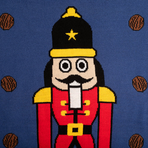 Stickat motiv av Nötknäpparen på en blå jultröja med bruna valnötter från Svenskhusman.