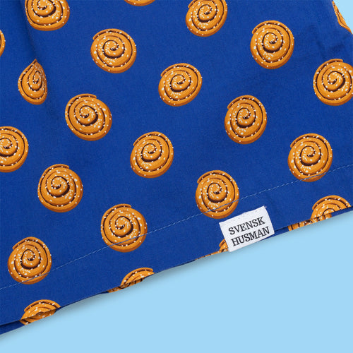 Blå unisex-boxershorts i bomull med mönster av kanelbullar och vit Svenskhusman-etikett.