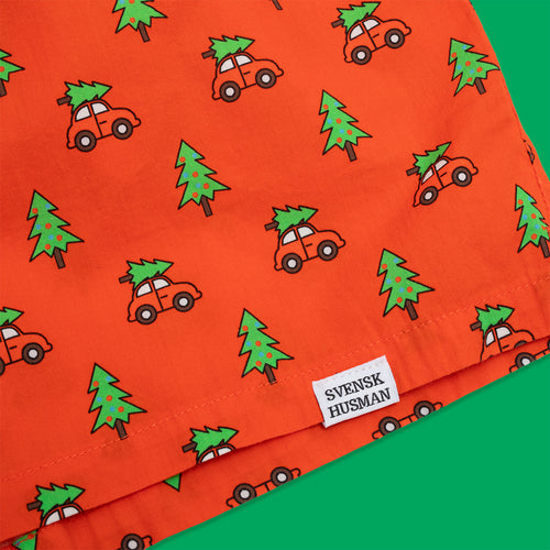 Röda boxershorts med mönster av granar på bilar och en vit Svenskhusman-etikett på bomullstyg.