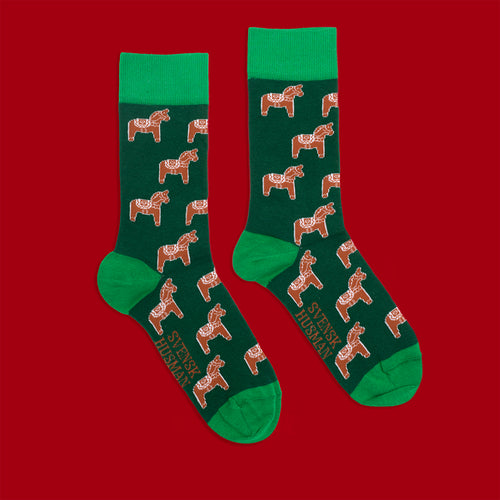 Grüna Socken med mönster av pepparkaksdalahästar och ljusgrüna detaljer på rot bakgrund från Schwedischhusman.