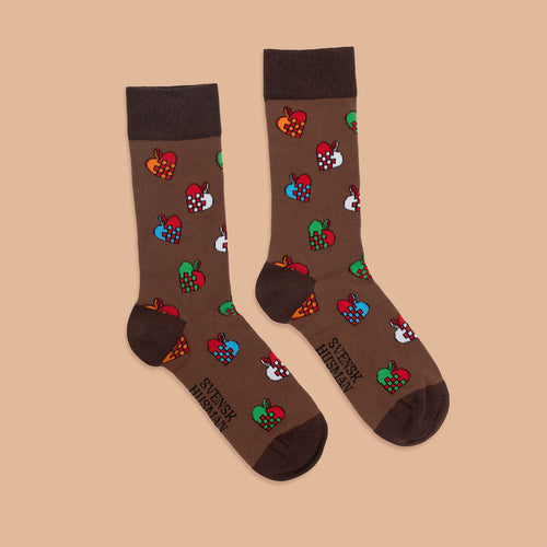 Brauna Socken med mönster av bunte flätade julhjärtan från Schwedischhusman på beige bakgrund.