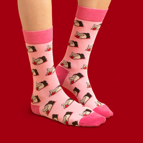 Rosa Socken med mönster av marsipangrisar från Schwedischhusman på en person mot rot bakgrund.