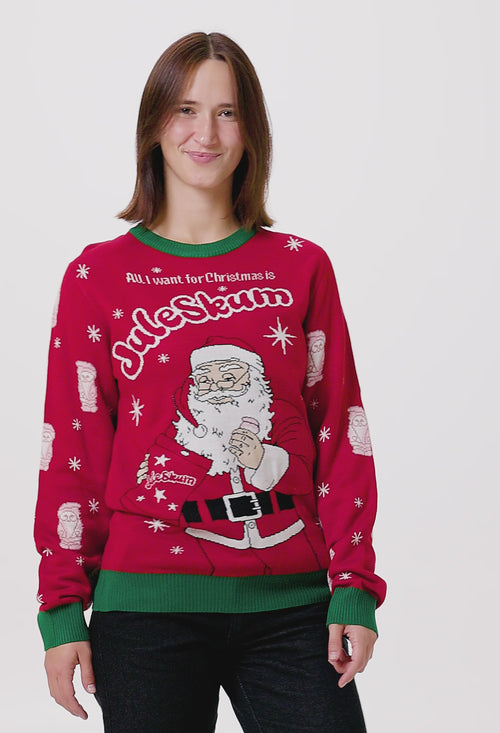Röd stickad jultröja för dam med Cloetta Juleskum-motiv, jultomte och gröna muddar på en person.