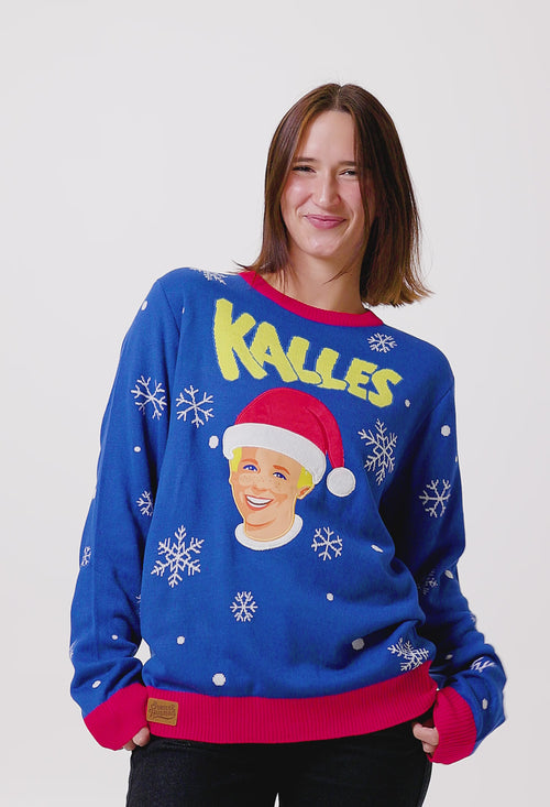 Blå jultröja för dam med Kalles Kaviar-motiv, snöflingor och röda detaljer på en person.